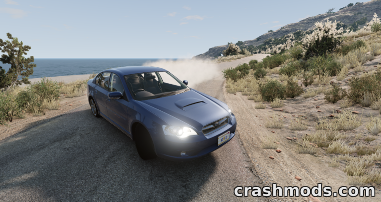 A blue Subaru Legacy drifts along a coastal road in BeamNG.drive, showcasing realistic vehicle dynamics.