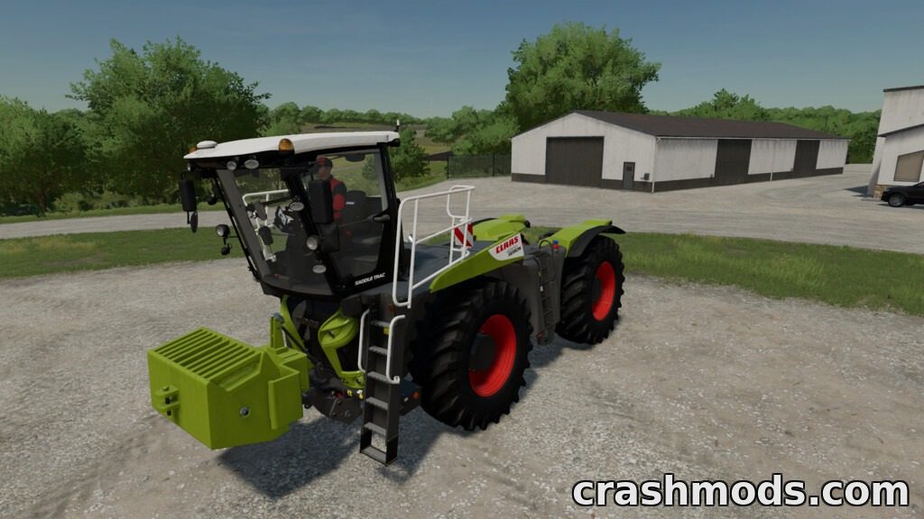 A green tractor equipped with an adjustable front weight, parked on a gravel area near farm buildings.