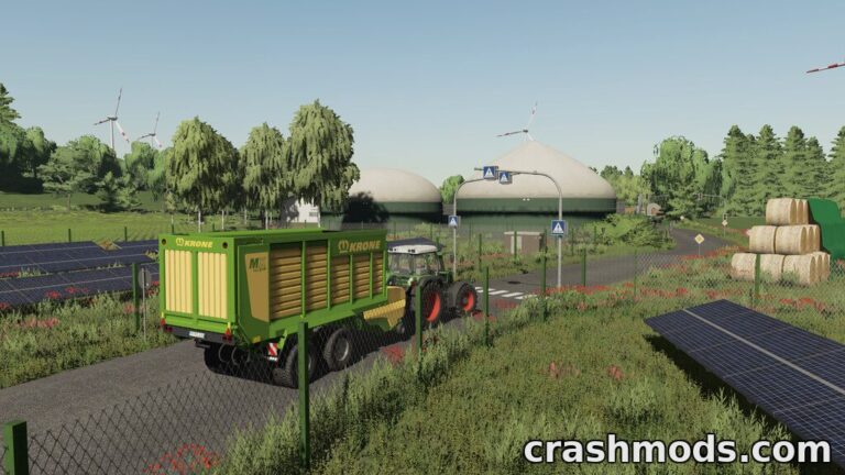 A tractor pulls a green trailer along a scenic road, surrounded by lush fields and solar panels in Schleswig-Holstein.