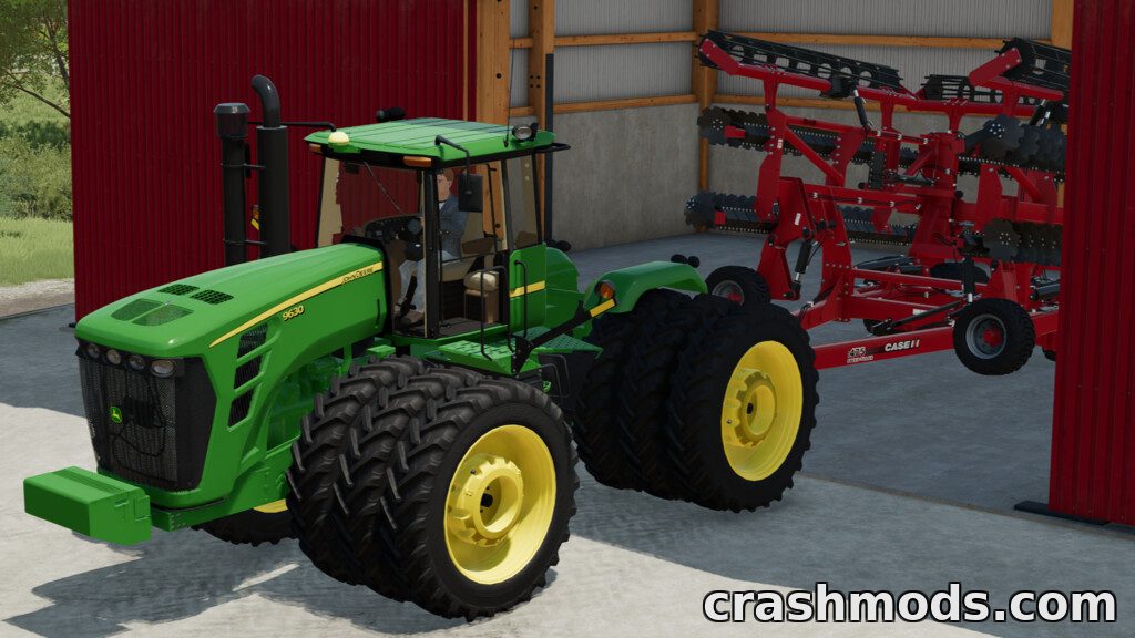 The John Deere 9020 tractor is parked inside a shed, ready to attach a red cultivator for Farming Simulator 22.