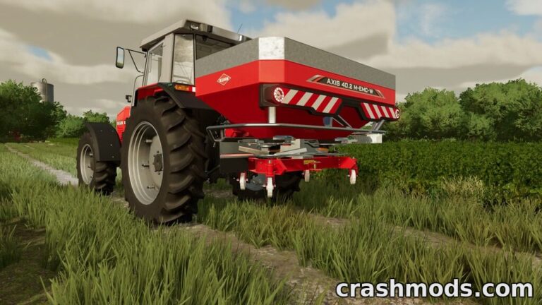 Kuhn Axis 402 fertilizer spreader attached to a tractor, ready for use in a lush farming landscape.